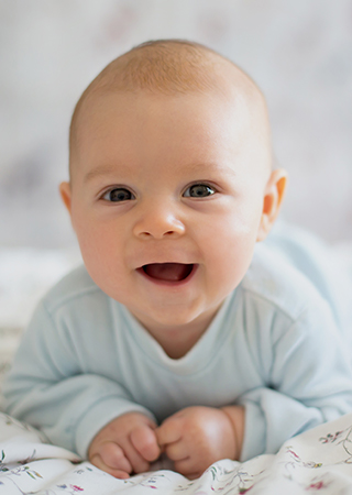 Smiling baby crawling on bed.