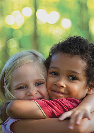 Smiling kids hugging at a park.