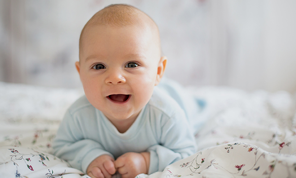 Smiling baby crawling on bed.