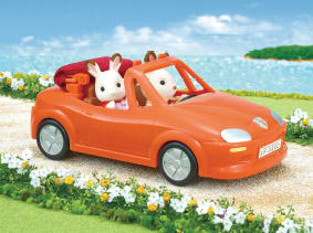 Two Sylvanians driving by the ocean side in an orange convertible car